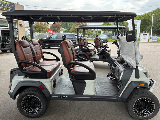 A white and black electric golf cart with brown leather seats, featuring the brand name 'EPIC' on the side, parked in an outdoor dealership lot.