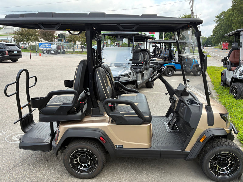 Load image into Gallery viewer, A luxury electric golf cart in champagne beige and black, parked outdoors in a dealership lot with other carts visible in the background.
