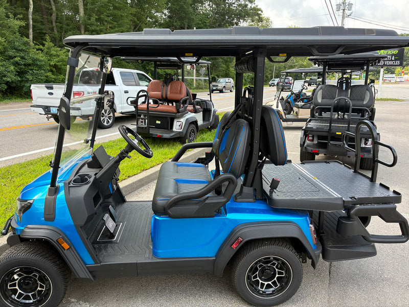Load image into Gallery viewer, A bright blue and black electric golf cart parked outdoors on a paved lot, with other golf carts visible in the background.
